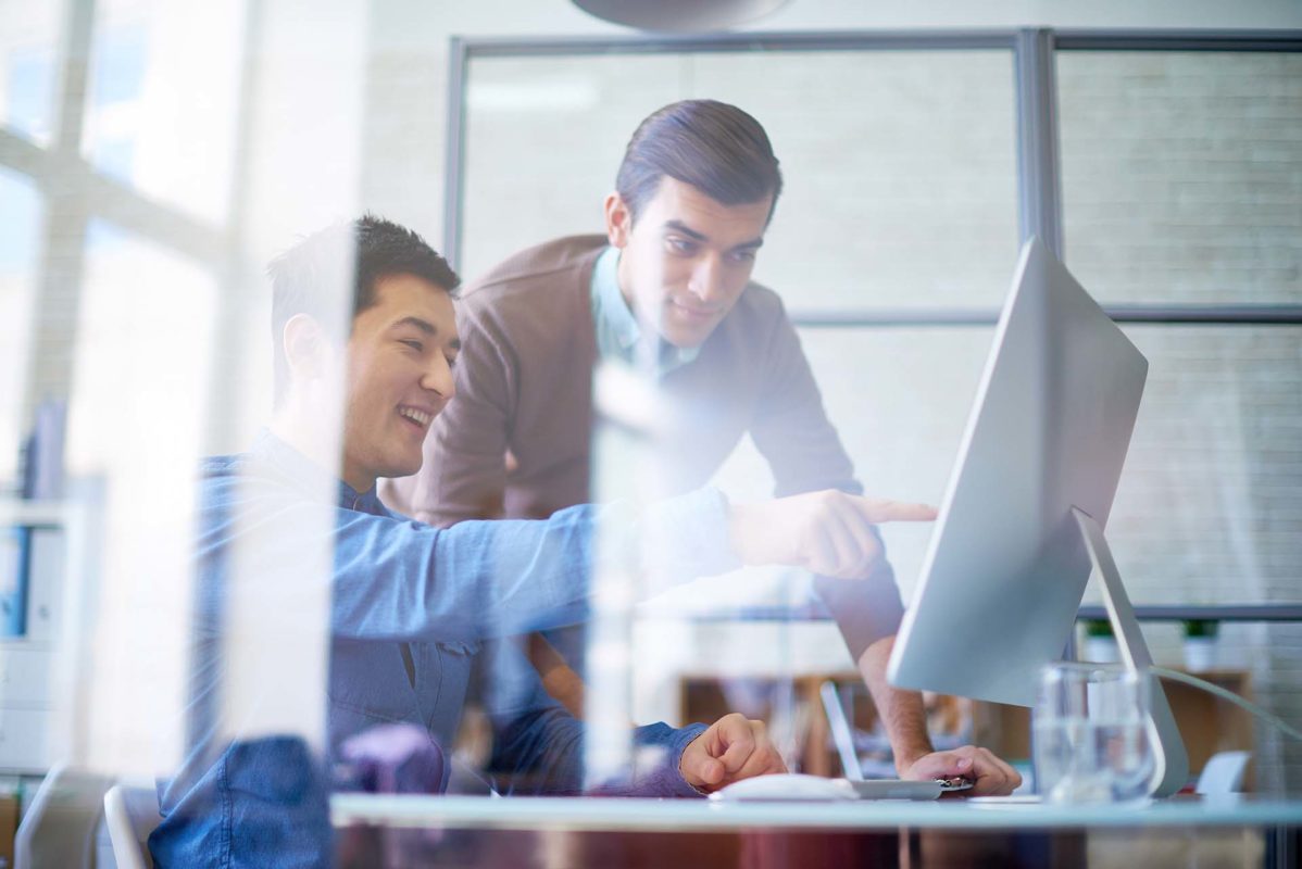 Two bankers looking at data analytics on a computer monitor.