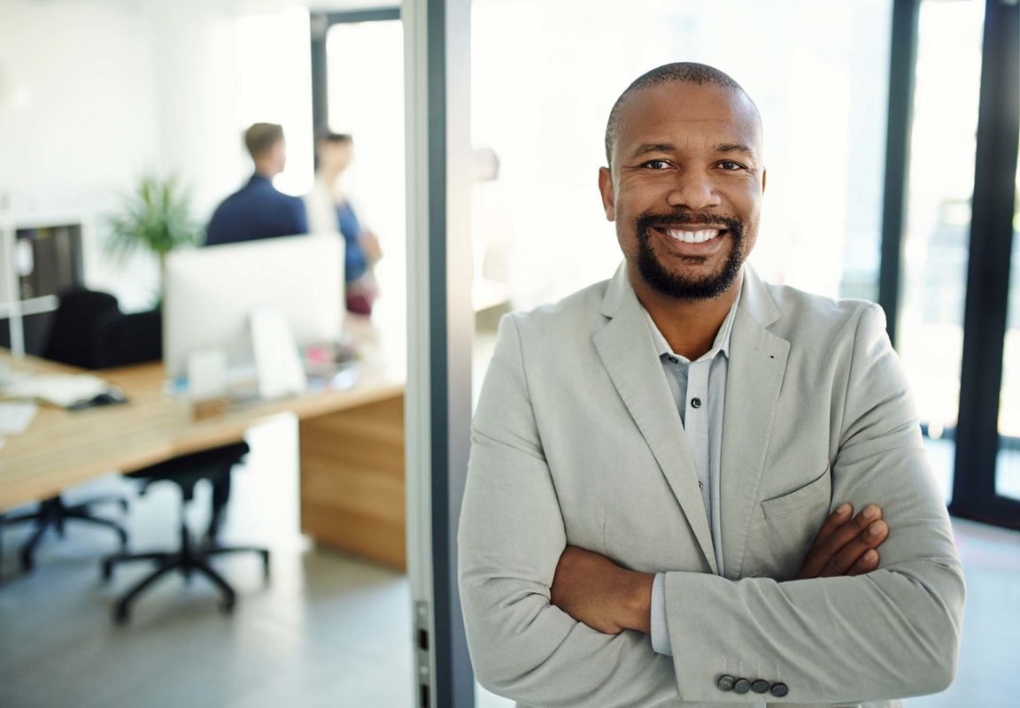 Portrait of a confident banker with his team in the background of a modern bank branch.