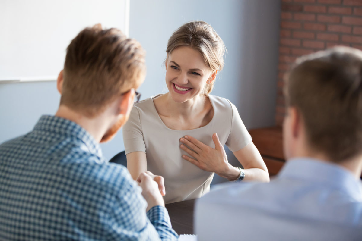 Back view of male worker shaking hand of happy satisfied female colleague or partner during office meeting, businessman complimenting woman, boss handshaking employee congratulating with success